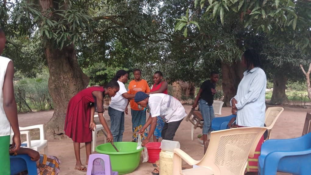 Séance de travail entre les associations de filles Fabrication et Production: Action des filles mélangeant la pâte à savon ou pétrissant la farine et le facilitateur de DEDI/Manono